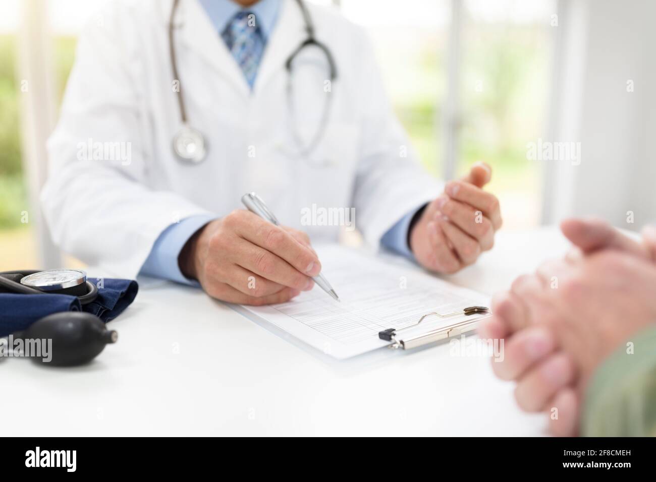 Il medico e il paziente a prendere appunti in medicina e chirurgia Foto Stock