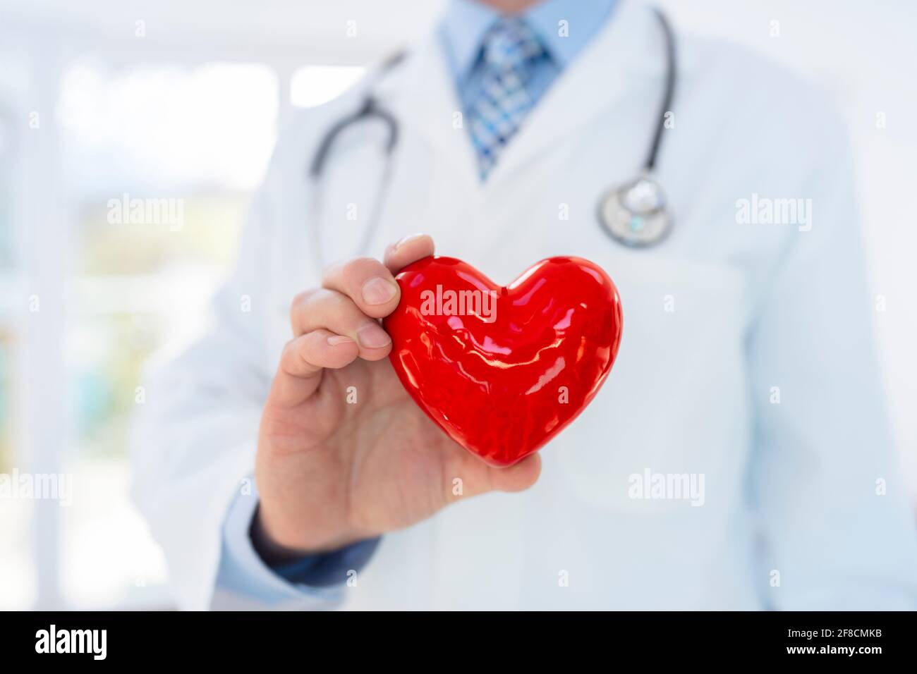 Medico o cardiologo che tiene il cuore con cura nelle mani a. concetto di ospedale per l'assistenza sanitaria e la diagnosi di pulsazioni cardiache mediche test Foto Stock