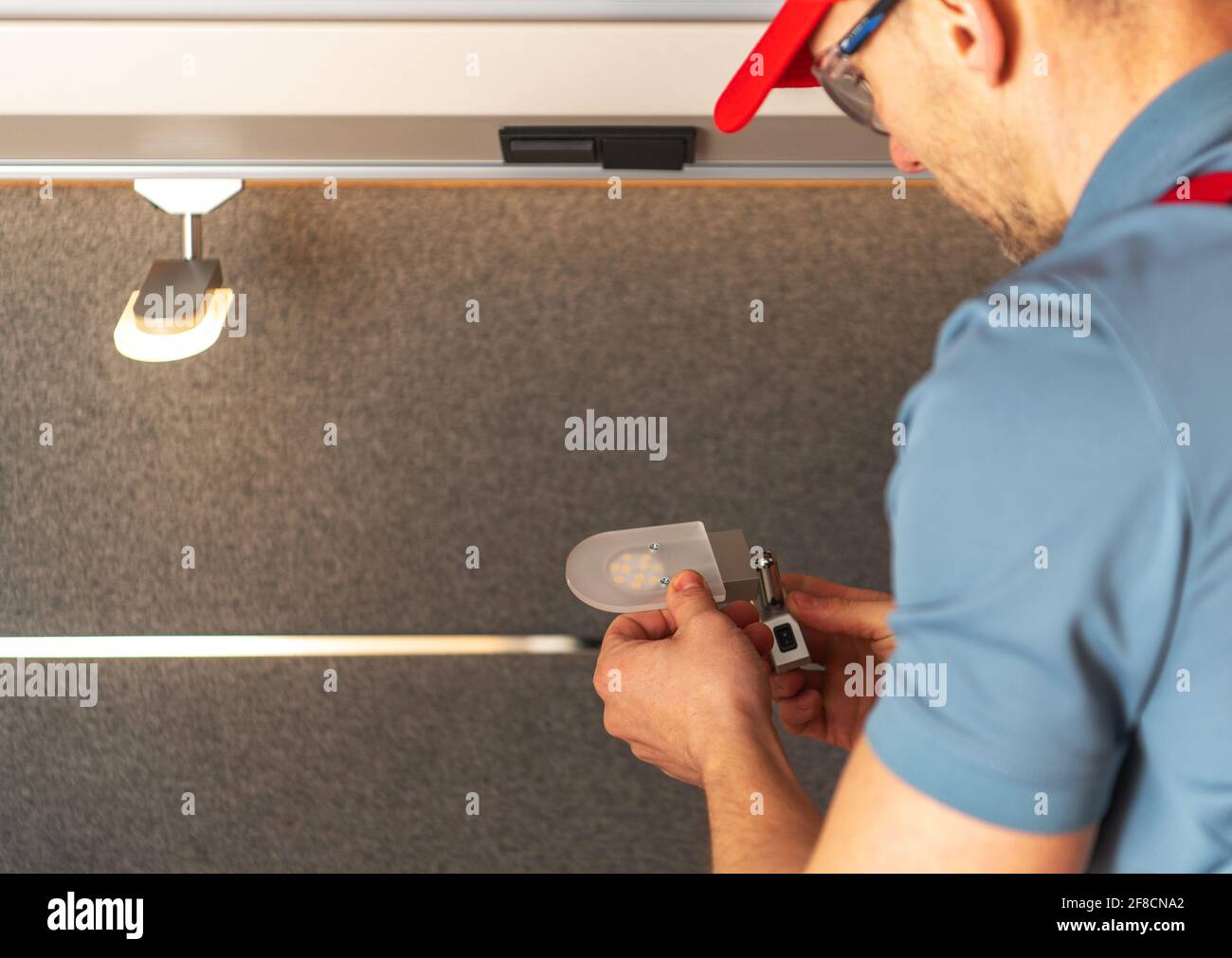 Sostituzione di Old RV Camper Lighting alle moderne luci a LED eseguite da un tecnico professionista di RV caucasico nei suoi 40 anni. Foto Stock