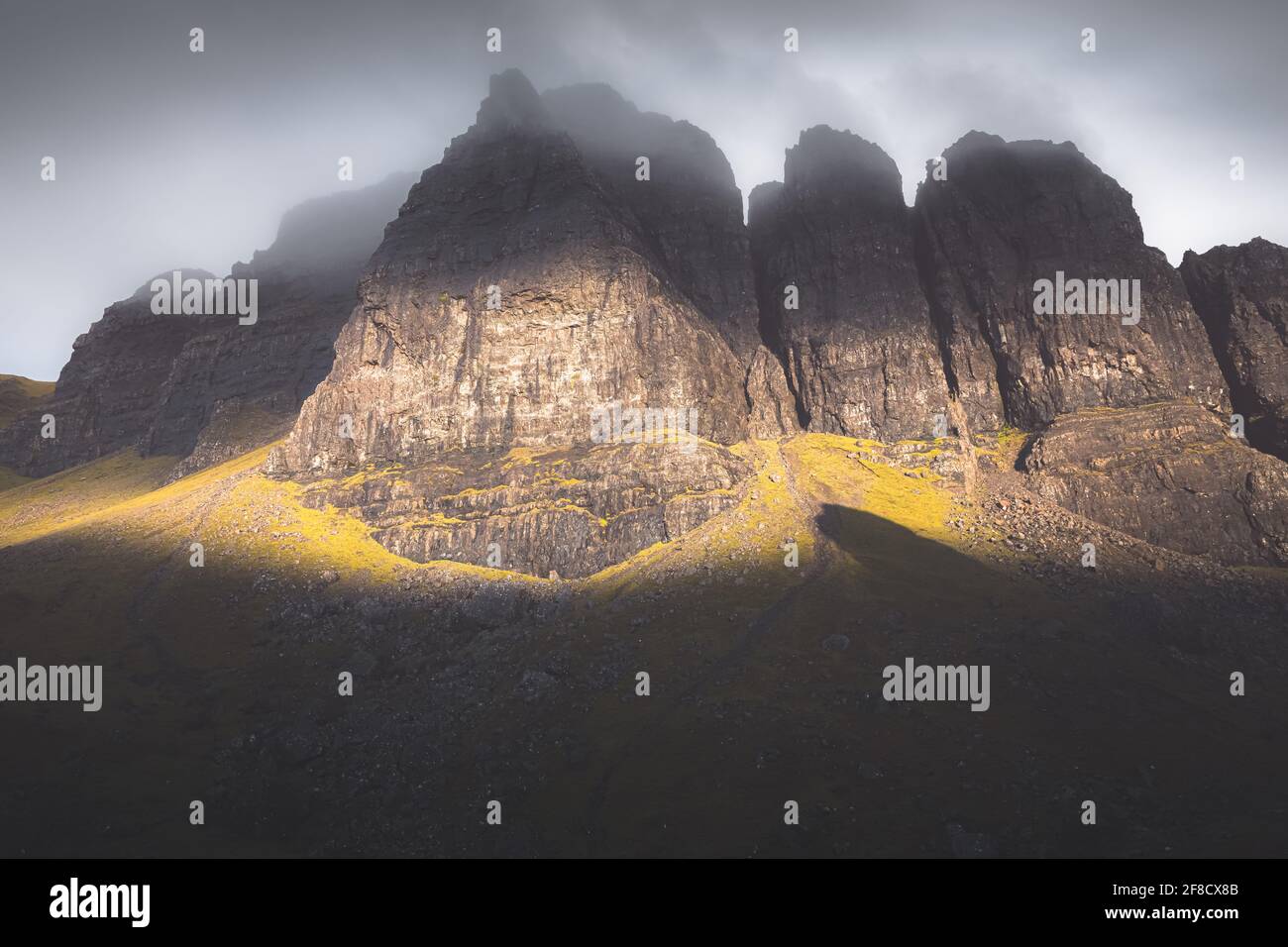 La luce e l'ombra drammatiche con foschia creano un paesaggio atomferico a forma di moodia scura presso la Storr sull'isola di Skye, nelle Highlands scozzesi. Foto Stock