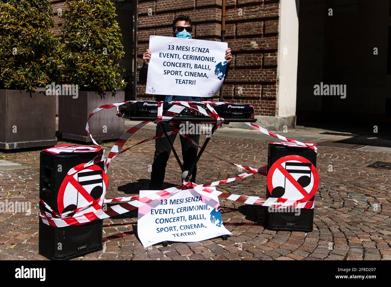 Torino, Italia. 13 aprile 2021: Un uomo tiene un cartello che legge '13 mesi senza eventi, cerimonie, concerti, danze, sport, cinema, teatri!' Dietro una tastiera musicale e altoparlanti durante una piccola impresa proprietari protesta organizzato da ASCOM. I proprietari italiani di piccole imprese, i ristoranti e le attività non primarie stanno protestando perché le loro attività sono chiuse per settimane e 250.000 posti di lavoro sono stati persi a causa del blocco del coronavirus COVID-19. Credit: Nicolò campo/Alamy Live News Foto Stock