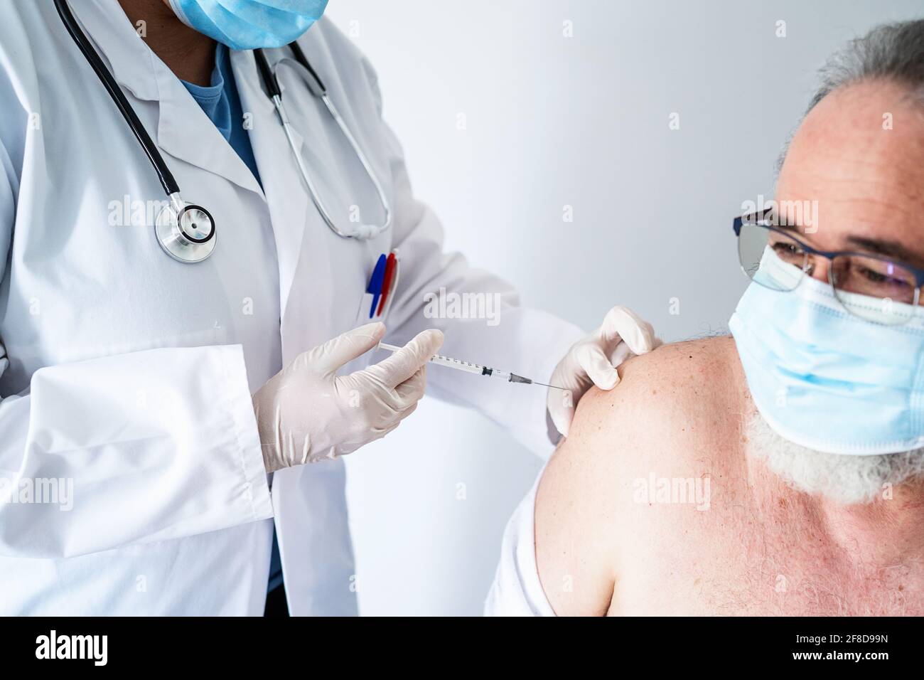 Primo piano di un'infermiera che vaccina un uomo anziano con Una maschera facciale con il vaccino Covid-19 Foto Stock