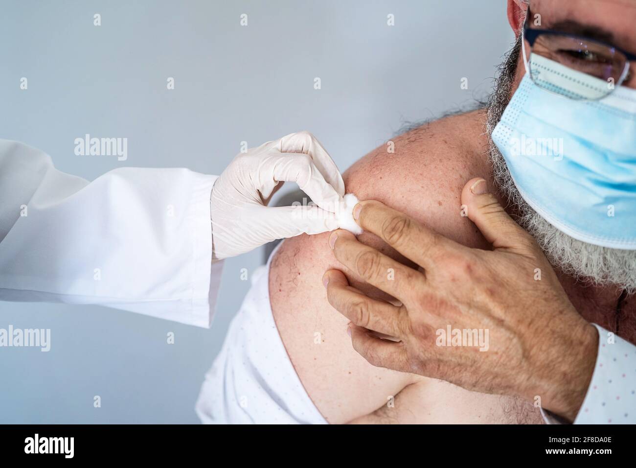 Uomo anziano con maschera facciale recentemente vaccinato con il Covid-19 vaccino Foto Stock