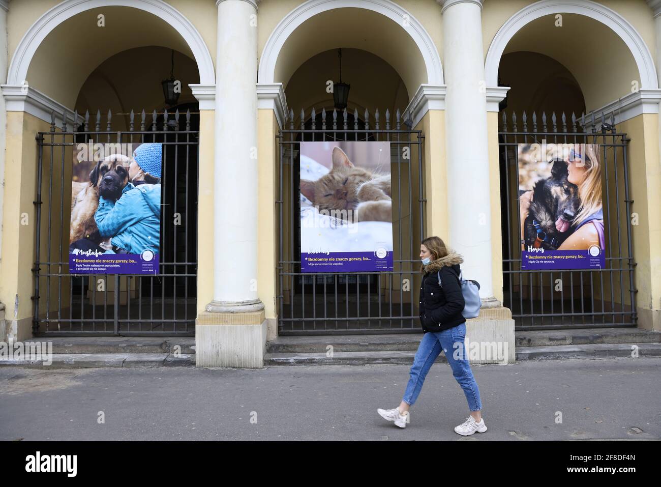 Una donna passa accanto a una mostra fotografica di animali domestici riparati a Varsavia, Polonia, il 10 aprile 2021. "Gli animali senza casa attraverso l'obiettivo" è una mostra fotografica Foto Stock