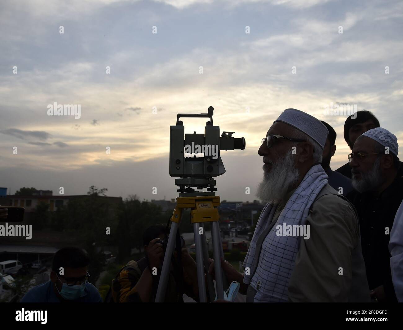 Peshawar. 13 Apr 2021. Un uomo osserva la luna crescente attraverso un telescopio nel Peshawar del Pakistan nord-occidentale il 13 aprile 2021. La luna a mezzaluna del Ramadan è stata avvistata in Pakistan martedì sera e il mese santo inizierà ufficialmente mercoledì, secondo un annuncio ufficiale del comitato di avvistamento della luna del paese. Credit: Saeed Ahmad/Xinhua/Alamy Live News Foto Stock