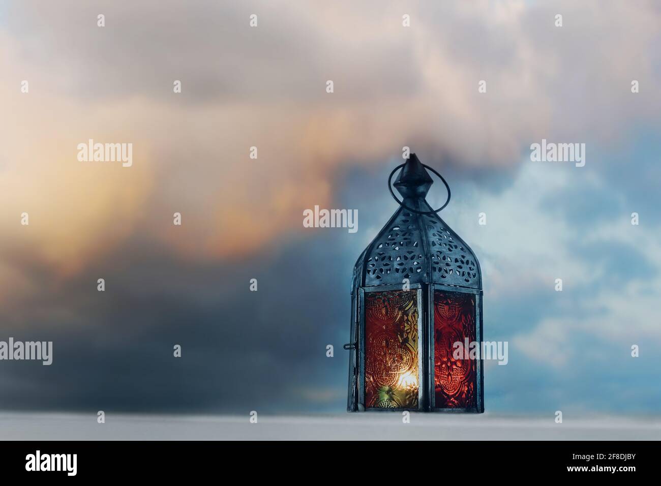 Vecchia lanterna Morrocana ardente al tramonto. Fumetto drammatico e offuscato cielo colorato e nuvole al crepuscolo. Ramadan Kareem biglietto d'auguri, invito. Musulmano Foto Stock