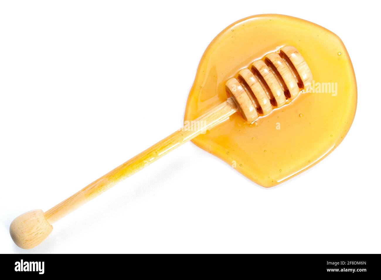 Il miele gocciola da un cucchiaia in una piscina di giallo dolce miele isolato su bianco con un ritaglio percorso Foto Stock