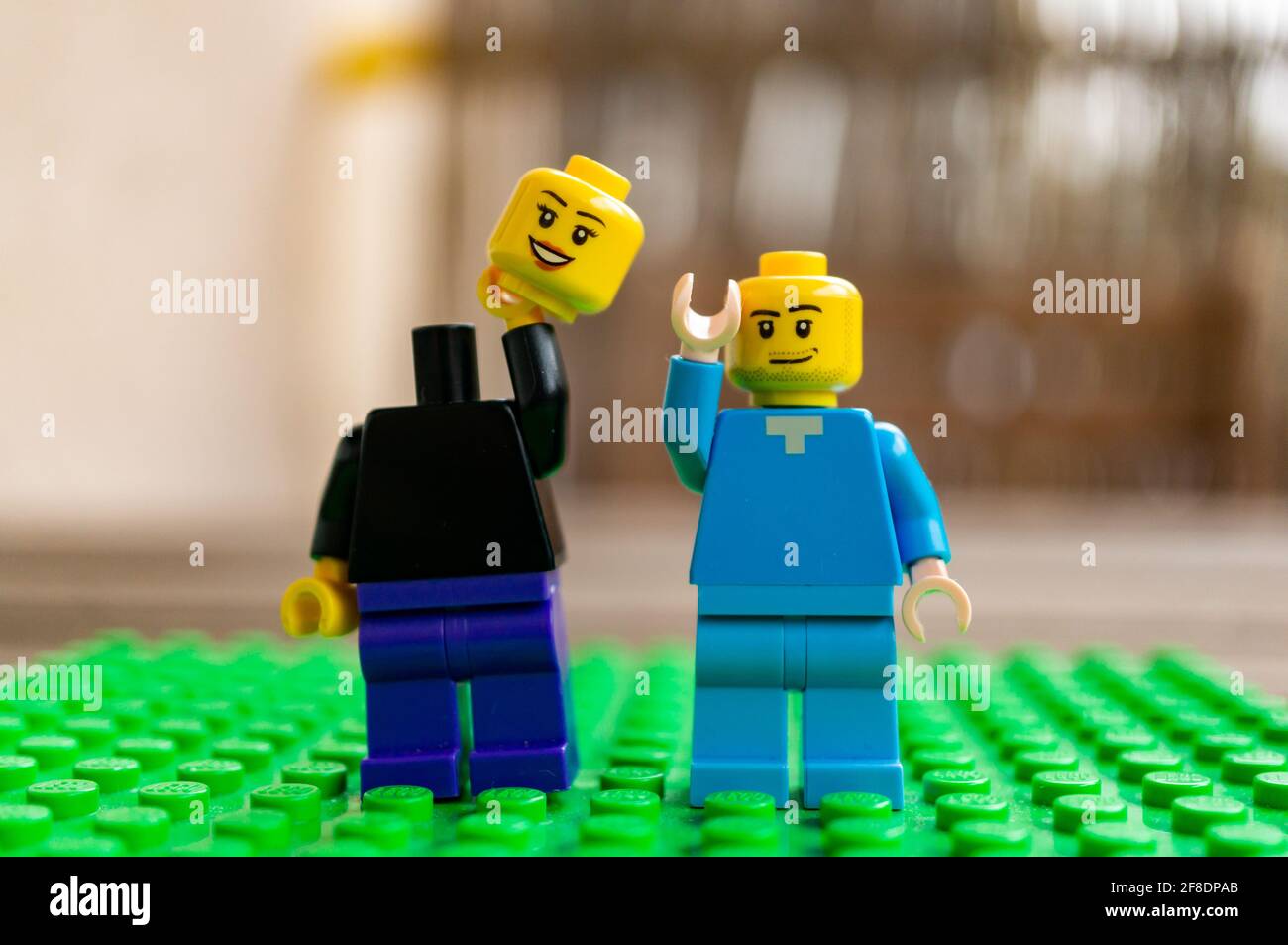 POZNAN, POLONIA - 27 marzo 2021: Due statuette giocattolo Lego in piedi su una superficie verde. Uno sta tenendo la testa mancante. Foto Stock