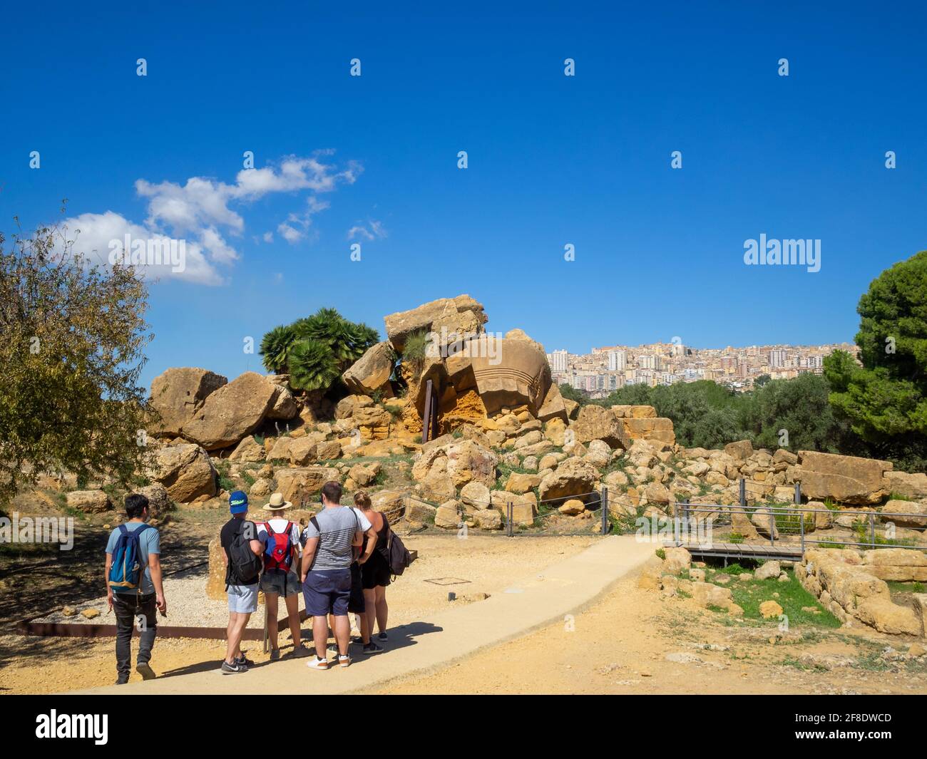 Turisti che ammirano le gigantesche colonne cadute del Tempio di Zeus Olimpio in Valle dei Templi Foto Stock