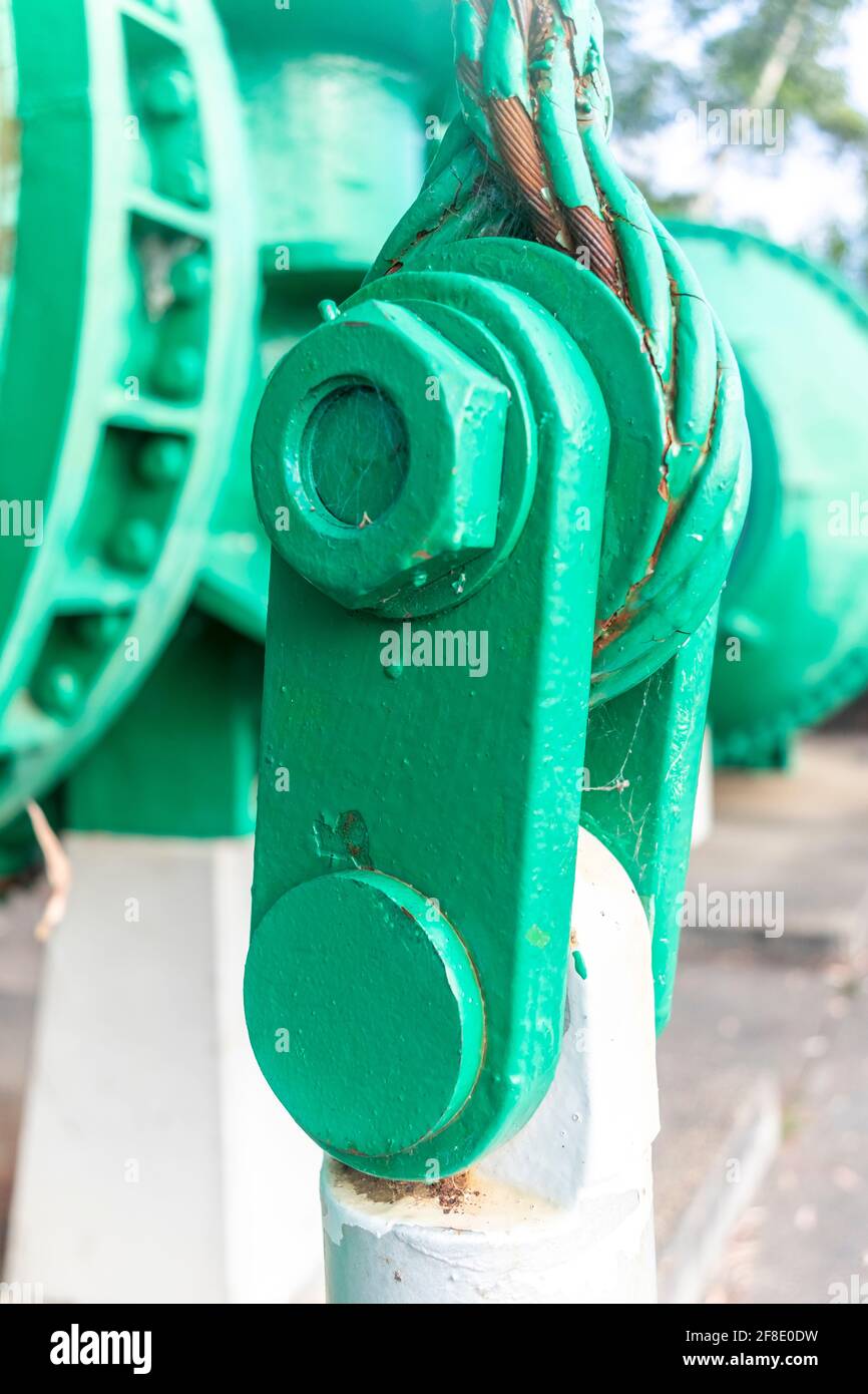 Vista ravvicinata di un vecchio arco di acciaio verde con un dado grande e un cavo in acciaio arrugginito Foto Stock