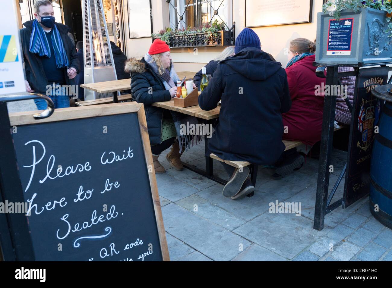 Amici e familiari gustatevi un pasto ad un tavolo all'aperto in Tragalgar Tavern Greenwich, Londra Foto Stock