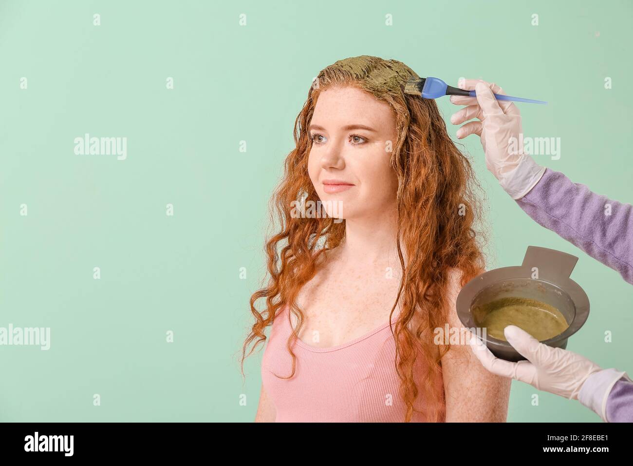 Tintura dei capelli della giovane donna con hennè su sfondo colorato Foto Stock