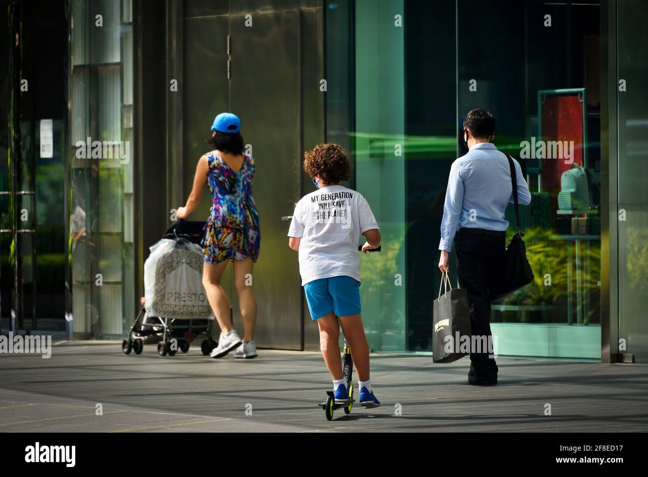 Ragazzo adolescente su scooter con maschera e T-shirt con Slogan "la mia generazione salverà il pianeta" su Orchard Road Singapore 13 aprile 2021 Foto Stock