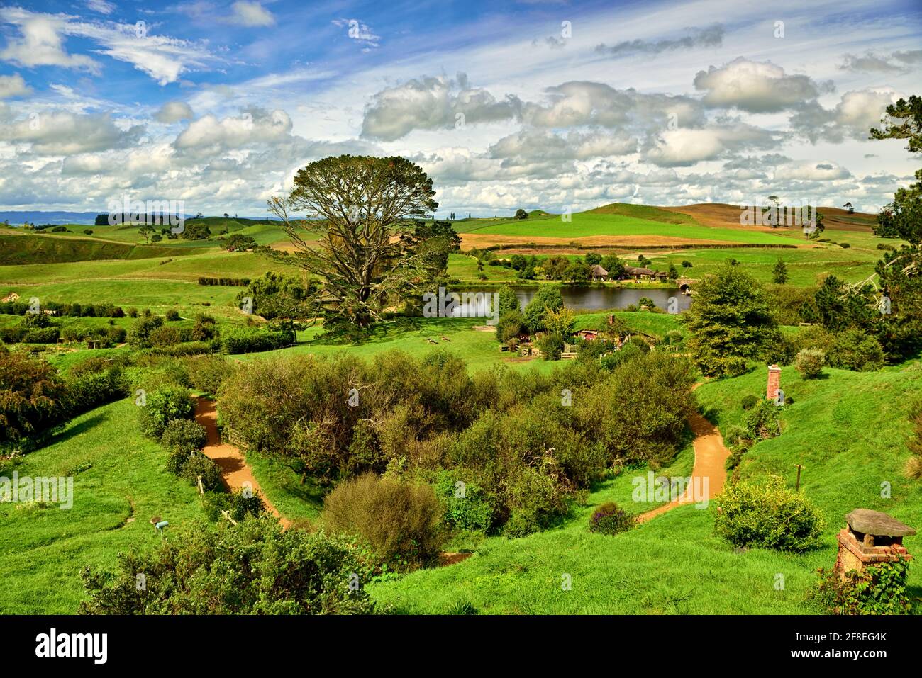 Nel cuore della campagna di Hamilton & Waikato, nascosta in modo tranquillo dietro verdi colline ondulate, è un luogo diverso da qualsiasi altro – Hobbiton Movie Set; The per Foto Stock