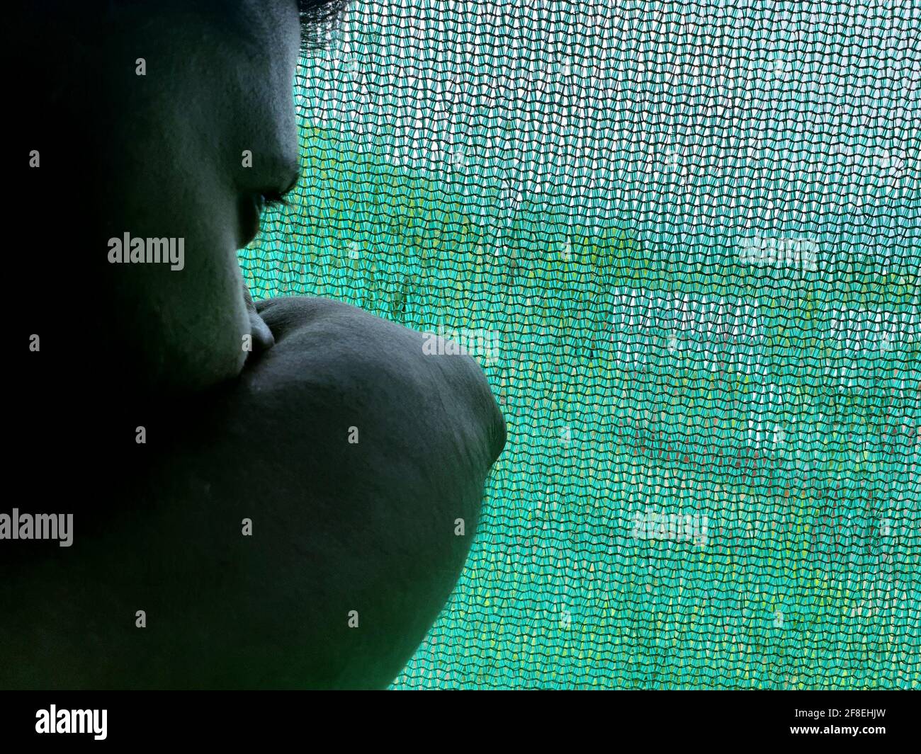 Una persona con maschera protettiva che guarda dalle finestre domestiche. La gente auto-isolando a casa, ha preso attraverso il loro specchio di finestre. Foto Stock