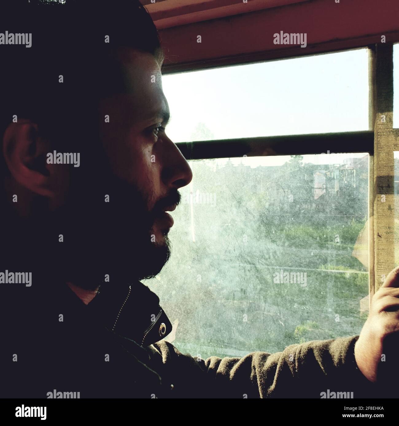 Una persona con maschera protettiva che guarda dalle finestre domestiche. La gente auto-isolando a casa, ha preso attraverso il loro specchio di finestre. Foto Stock