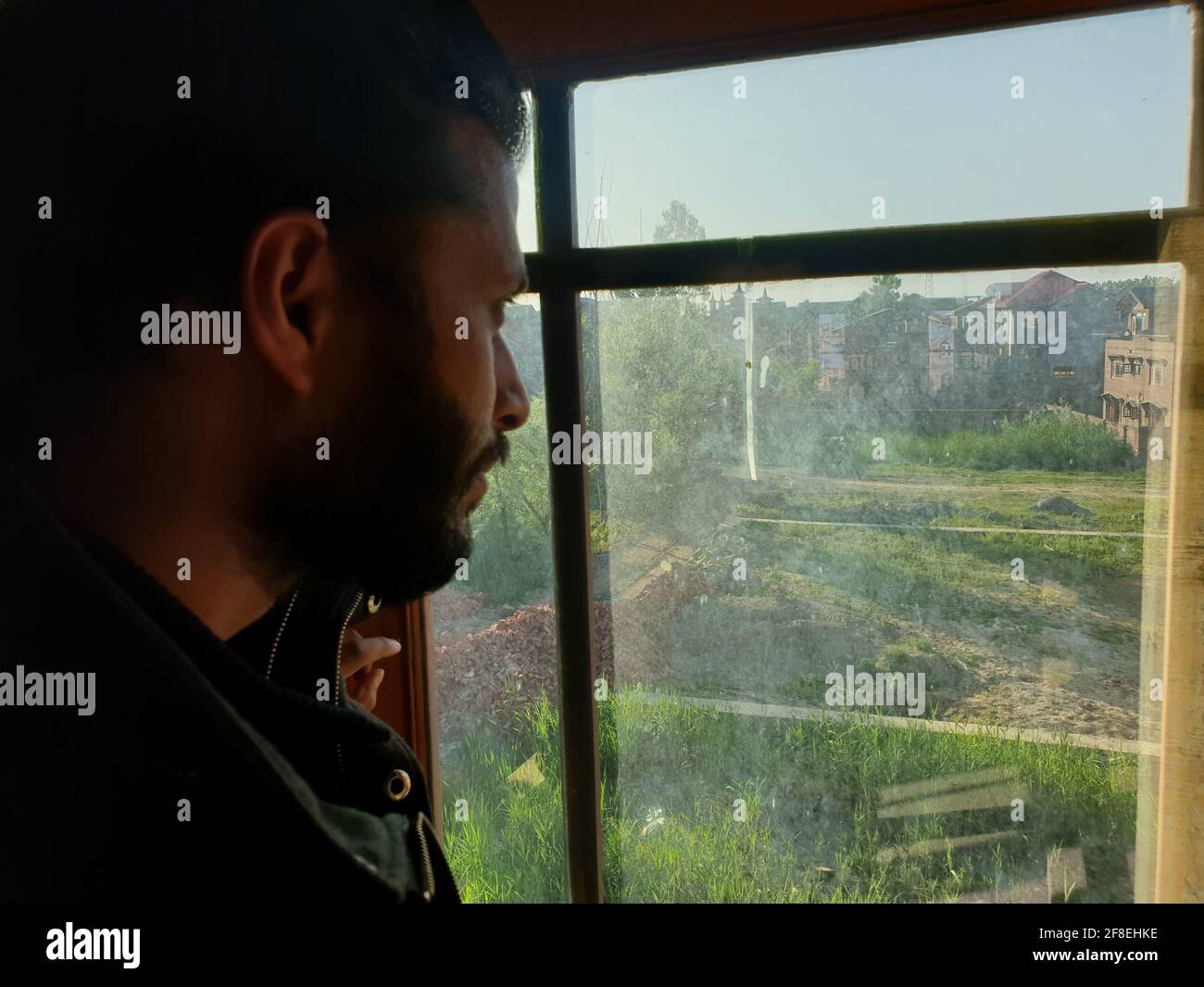 Una persona con maschera protettiva che guarda dalle finestre domestiche. La gente auto-isolando a casa, ha preso attraverso il loro specchio di finestre. Foto Stock