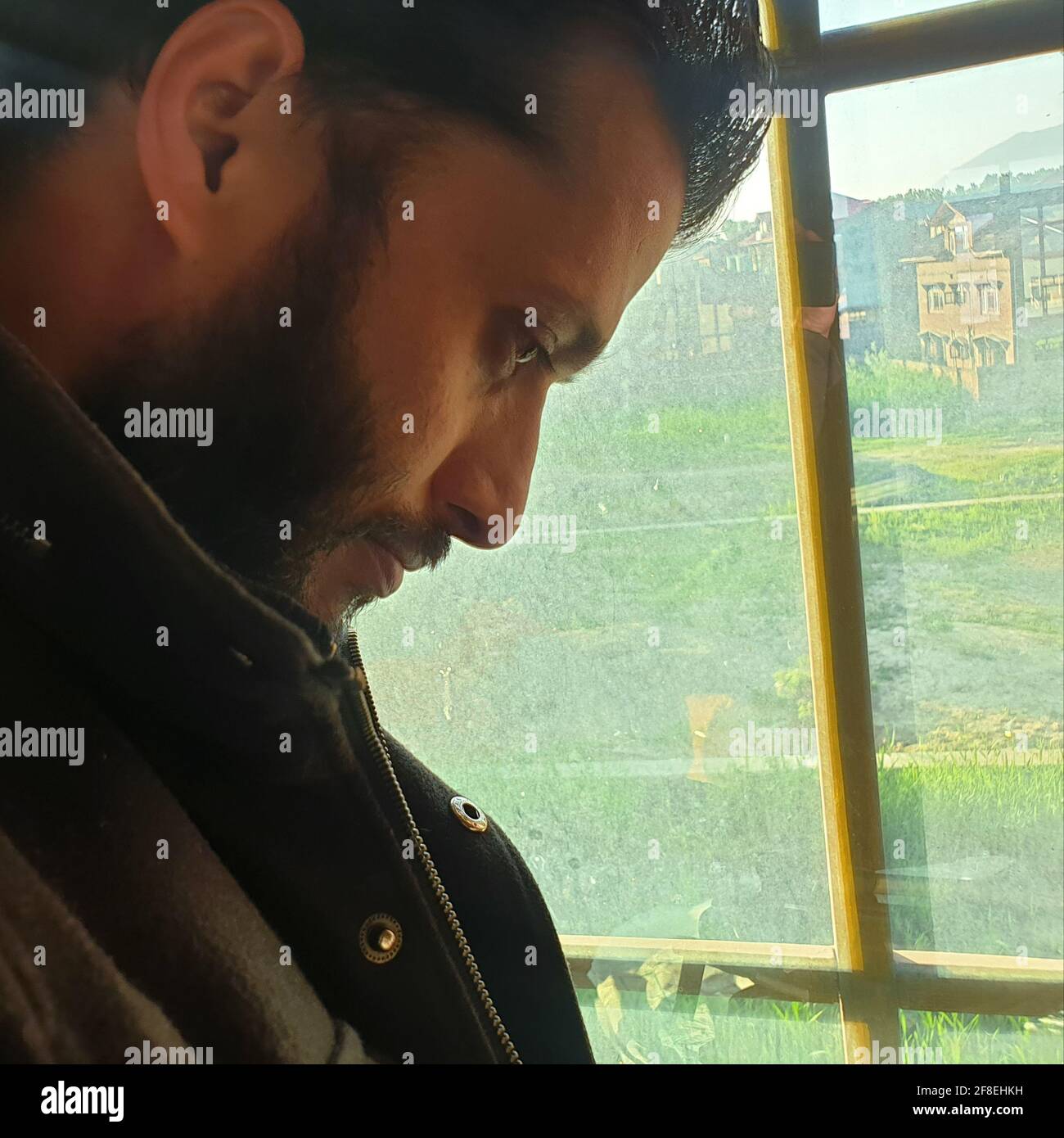 Una persona con maschera protettiva che guarda dalle finestre domestiche. La gente auto-isolando a casa, ha preso attraverso il loro specchio di finestre. Foto Stock