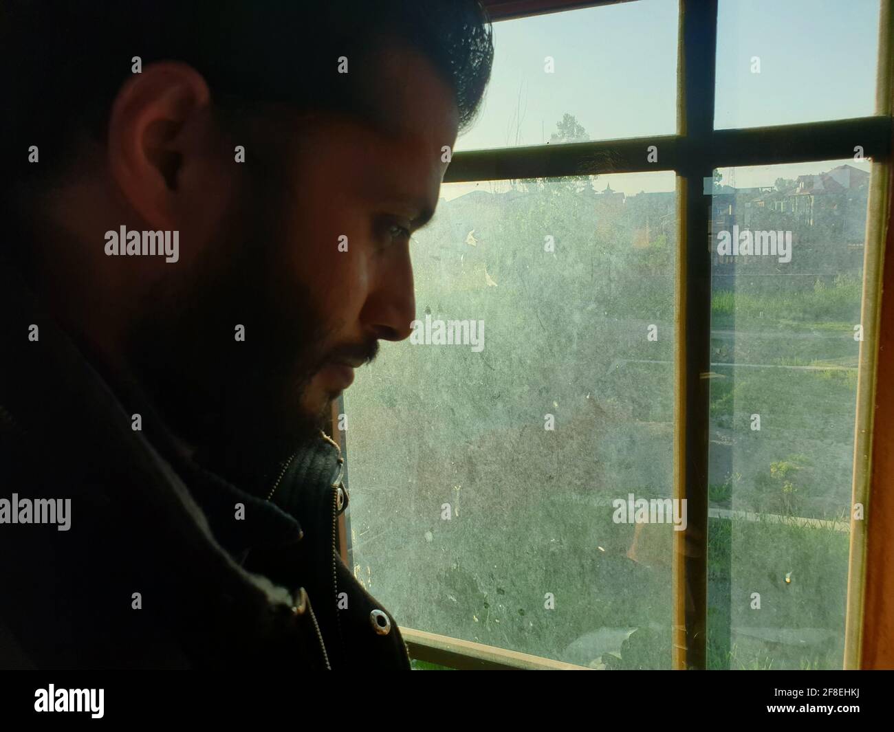 Una persona con maschera protettiva che guarda dalle finestre domestiche. La gente auto-isolando a casa, ha preso attraverso il loro specchio di finestre. Foto Stock