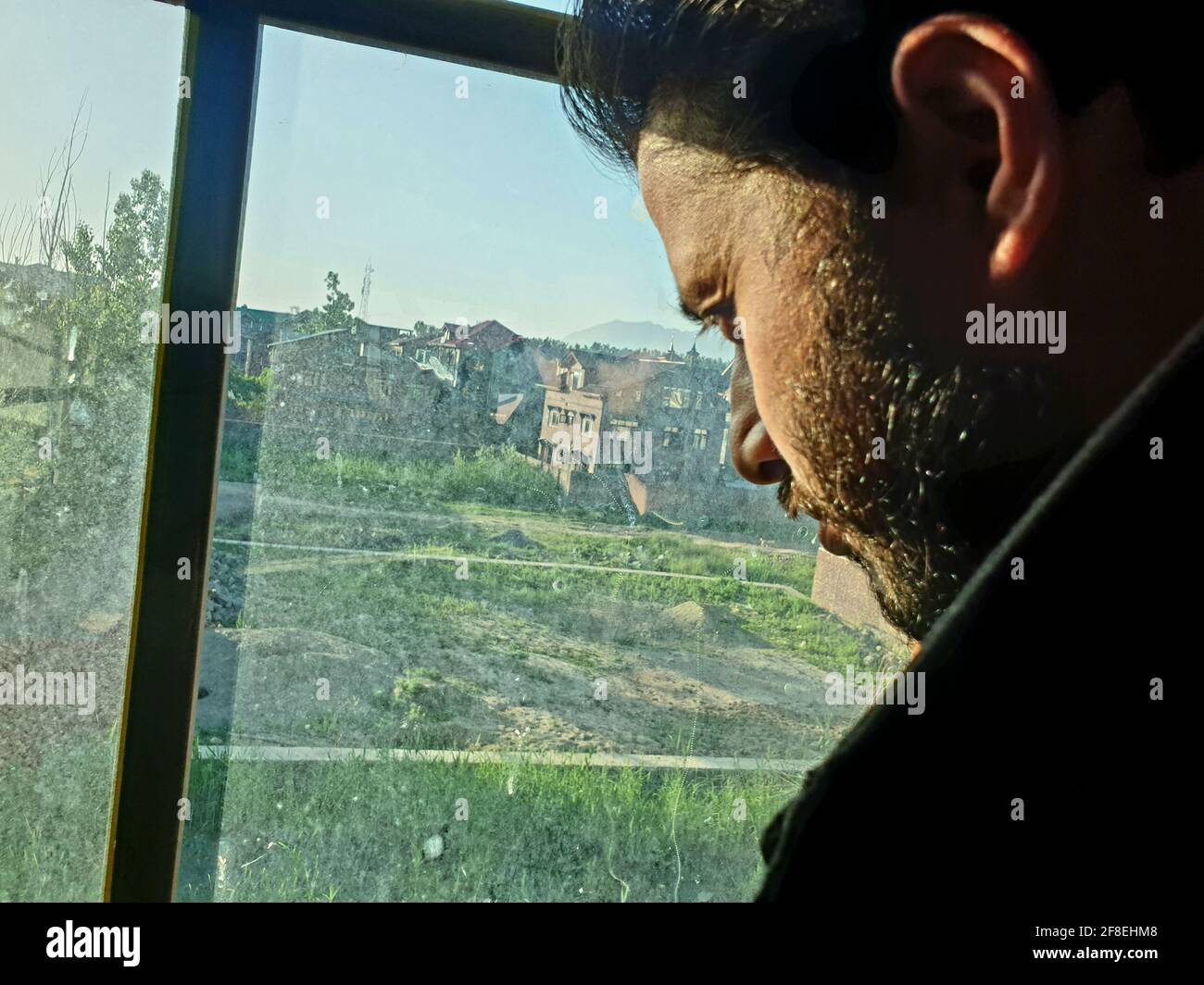 Una persona con maschera protettiva che guarda dalle finestre domestiche. La gente auto-isolando a casa, ha preso attraverso il loro specchio di finestre. Foto Stock