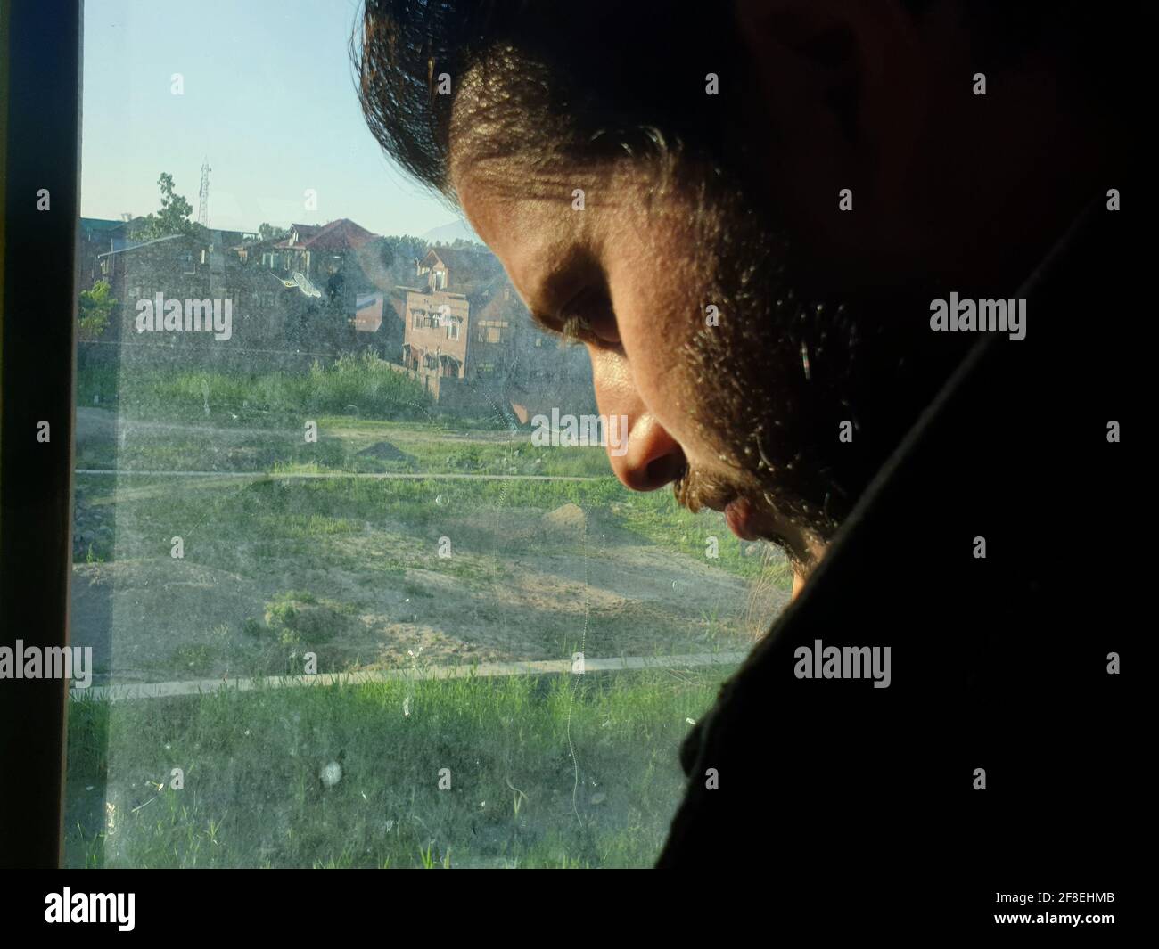 Una persona con maschera protettiva che guarda dalle finestre domestiche. La gente auto-isolando a casa, ha preso attraverso il loro specchio di finestre. Foto Stock