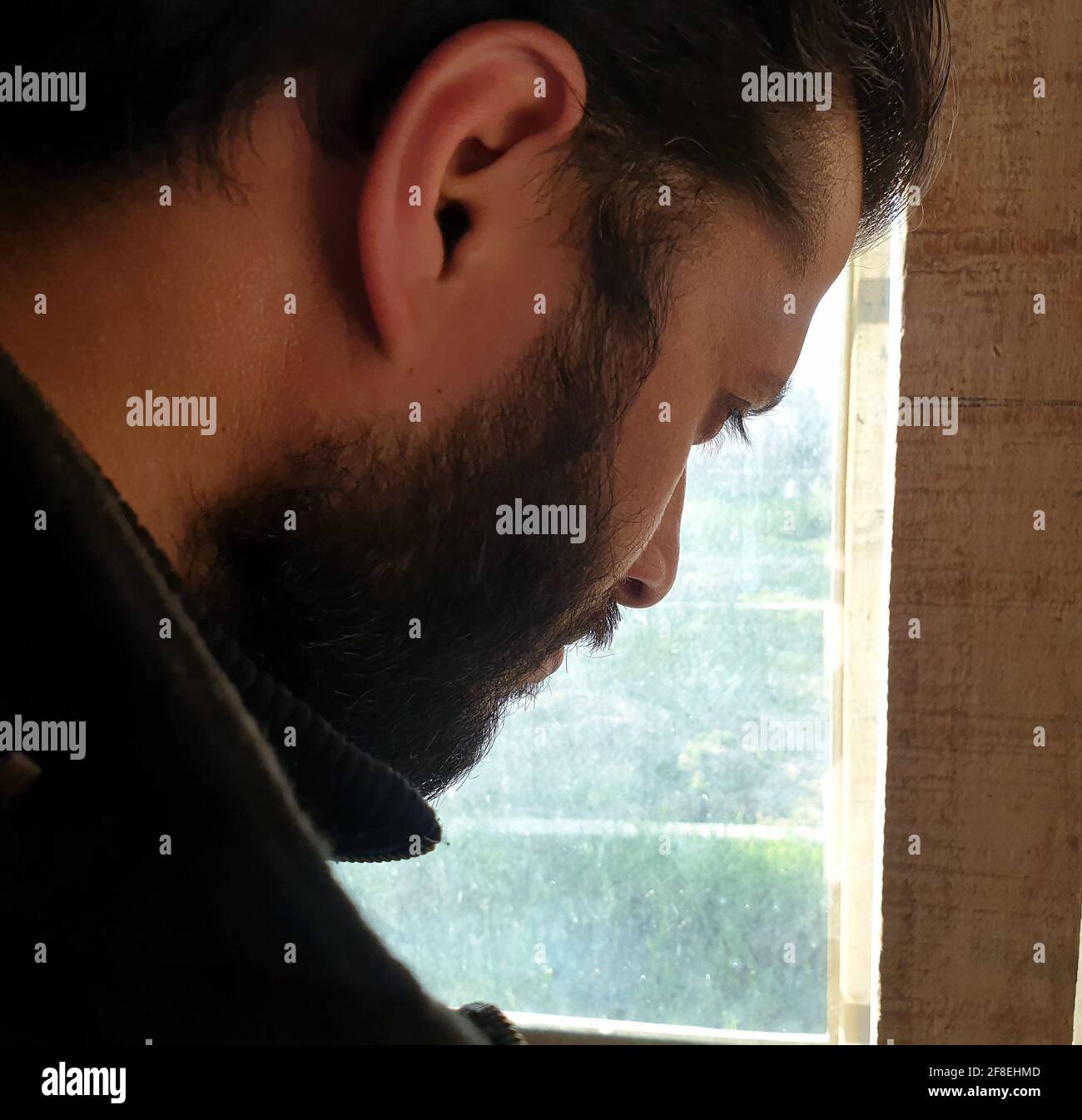 Una persona con maschera protettiva che guarda dalle finestre domestiche. La gente auto-isolando a casa, ha preso attraverso il loro specchio di finestre. Foto Stock