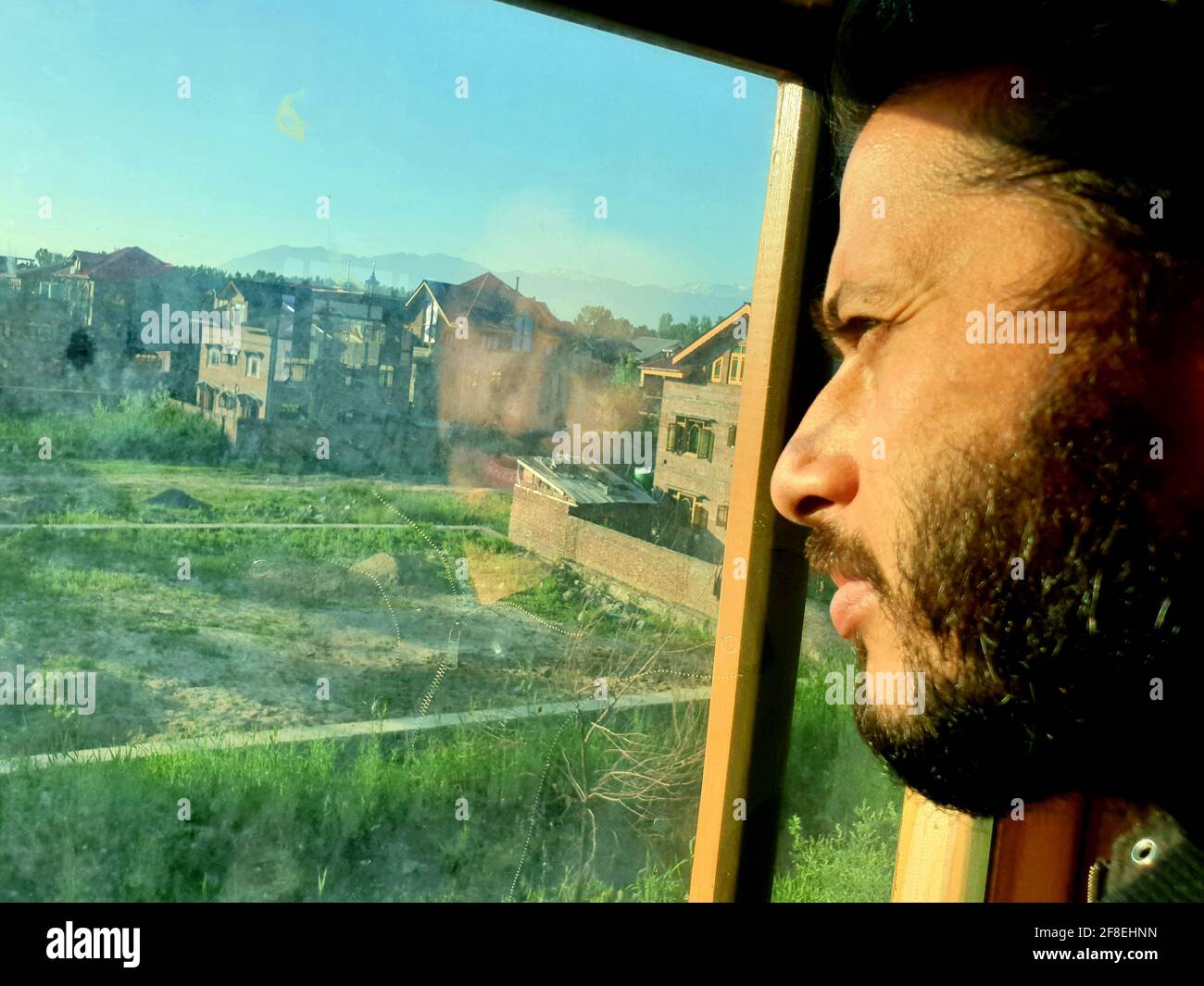 Una persona con maschera protettiva che guarda dalle finestre domestiche. La gente auto-isolando a casa, ha preso attraverso il loro specchio di finestre. Foto Stock