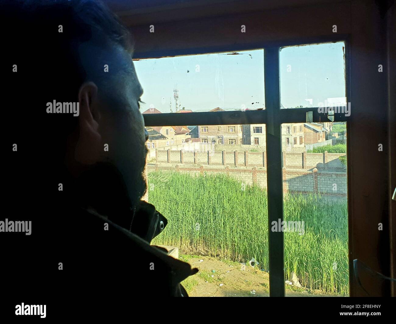 Una persona con maschera protettiva che guarda dalle finestre domestiche. La gente auto-isolando a casa, ha preso attraverso il loro specchio di finestre. Foto Stock