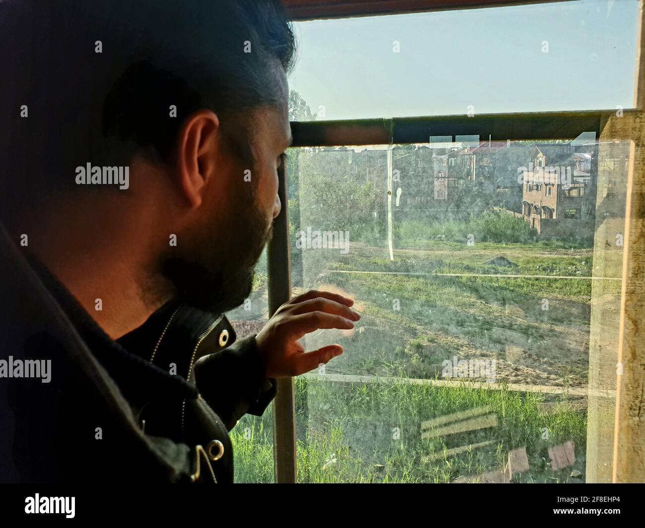 Una persona con maschera protettiva che guarda dalle finestre domestiche. La gente auto-isolando a casa, ha preso attraverso il loro specchio di finestre. Foto Stock