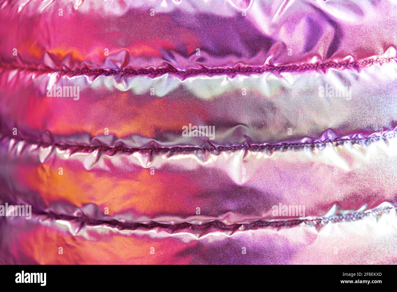 La texture iridescente del tessuto bolognese della giacca giovanile trapuntata. Neon rosa in stile trendy sfondo. Foto Stock
