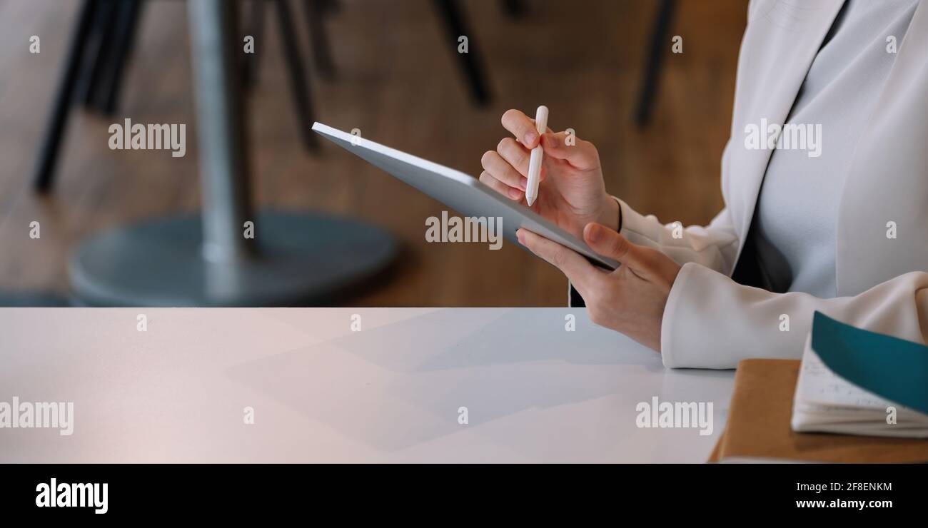 Primo piano donna d'affari tiene penna stilo disegno su tablet digitale sul posto di lavoro Foto Stock