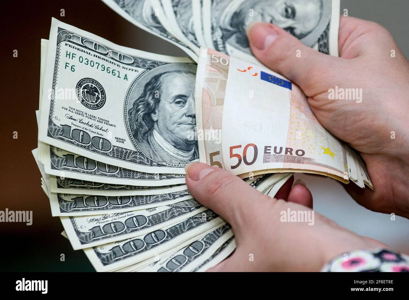 Minsk. Bielorussia - 17.04.2009: Bollette da cento dollari e banconote da 50 euro in una mano su sfondo grigio. Foto Stock