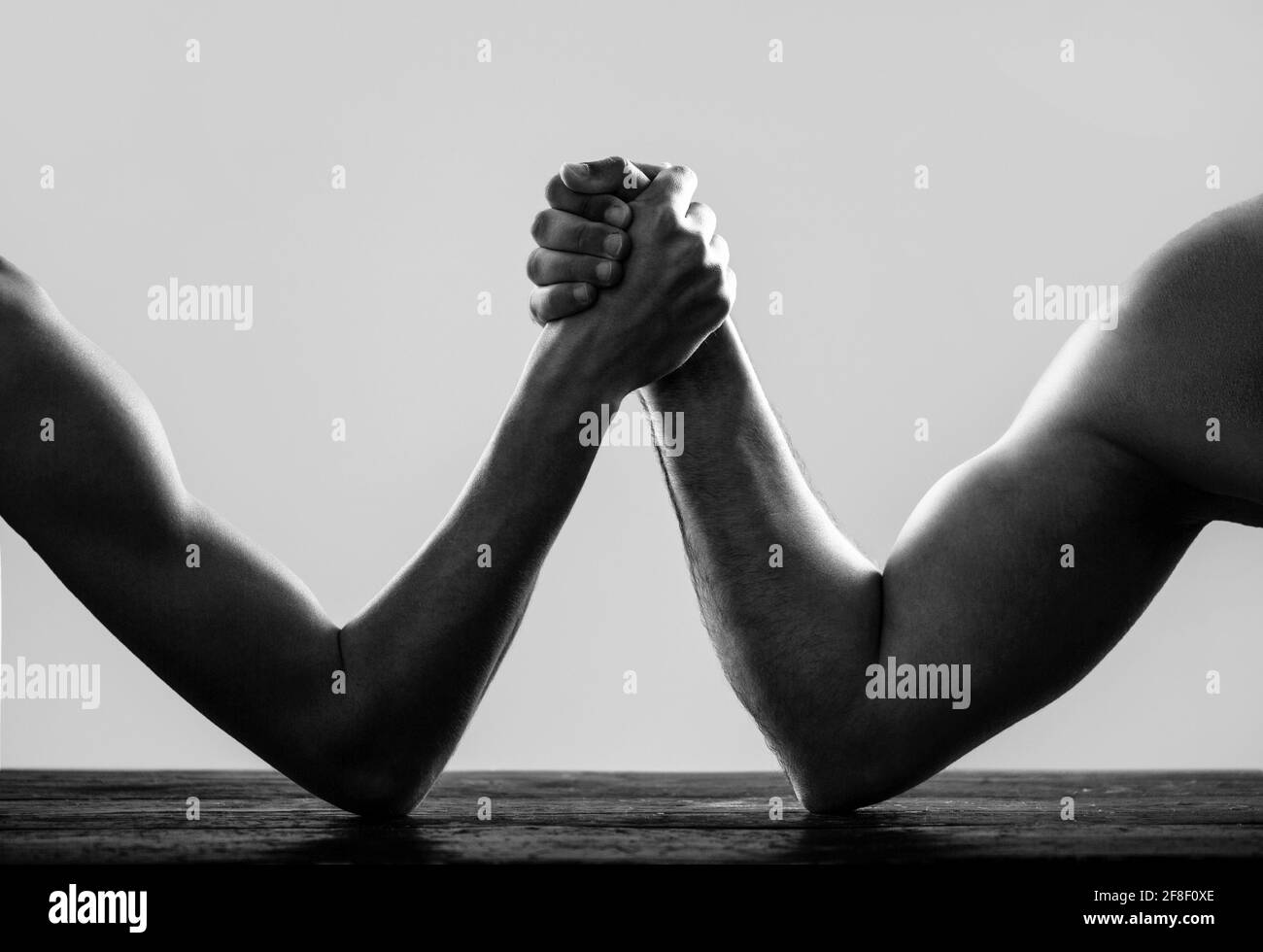 Armi che lottano con la mano sottile e un grande braccio forte in studio. Braccio wrestling. Braccio uomo molto muscled che lotta un uomo debole puny. Due mani dell'uomo si sono aggrappate al braccio Foto Stock