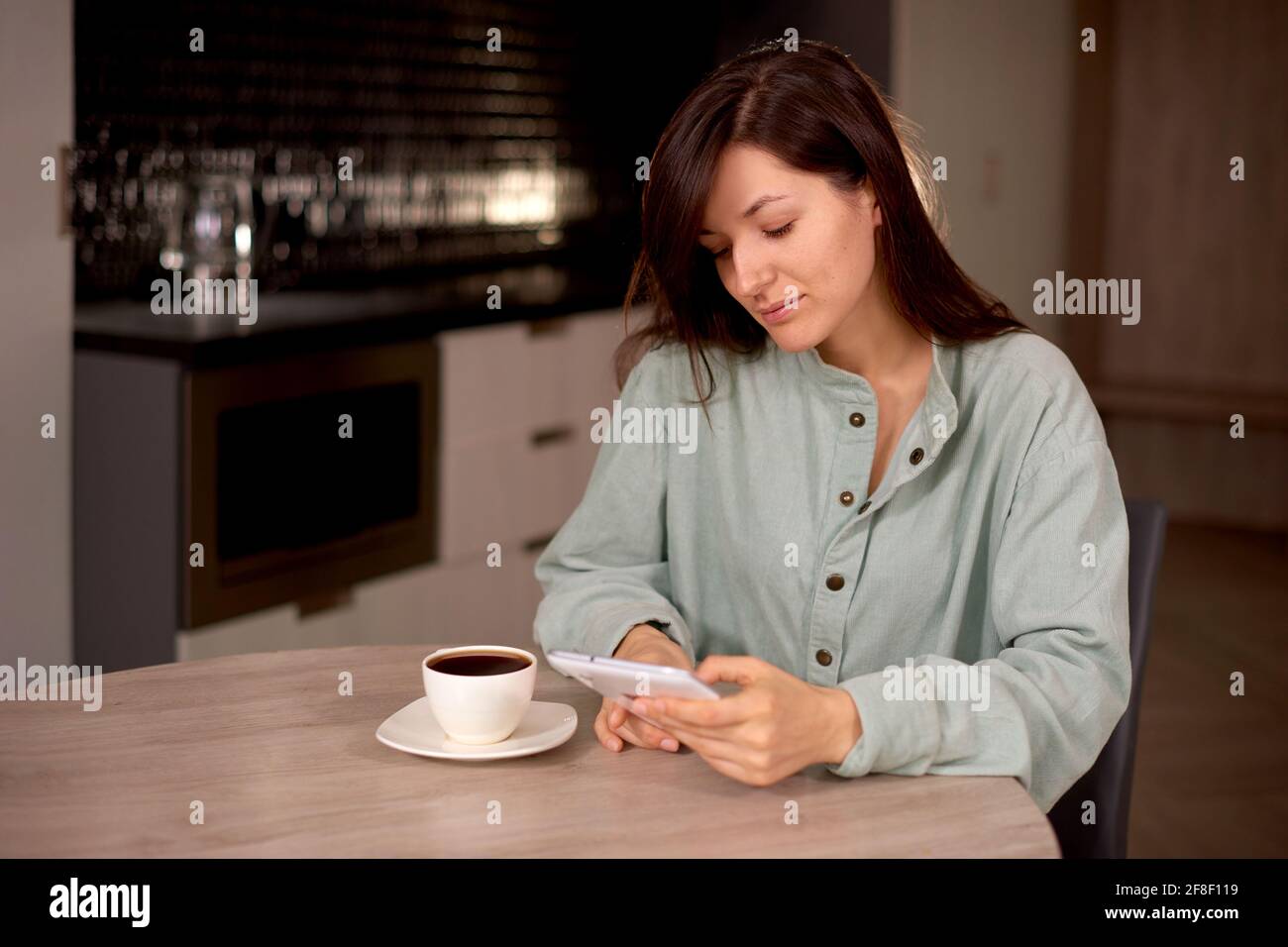 donna usa il tablet a casa con una tazza di caffè o tè in cucina. donna comunica in social network o sito web di riunione Foto Stock