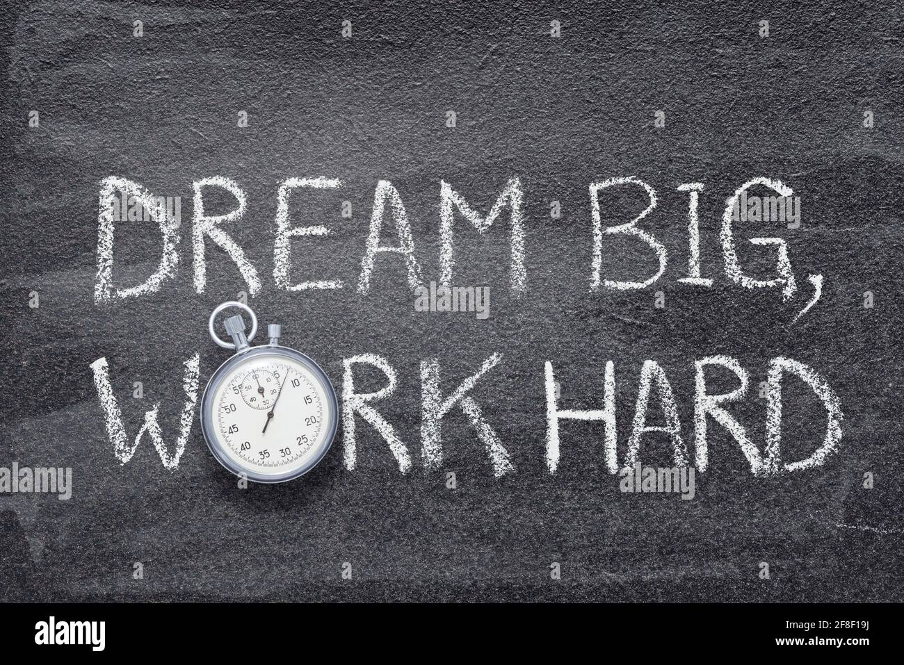 dream grande, lavorare duro slogan scritto su lavagna con cronometro vintage preciso Foto Stock