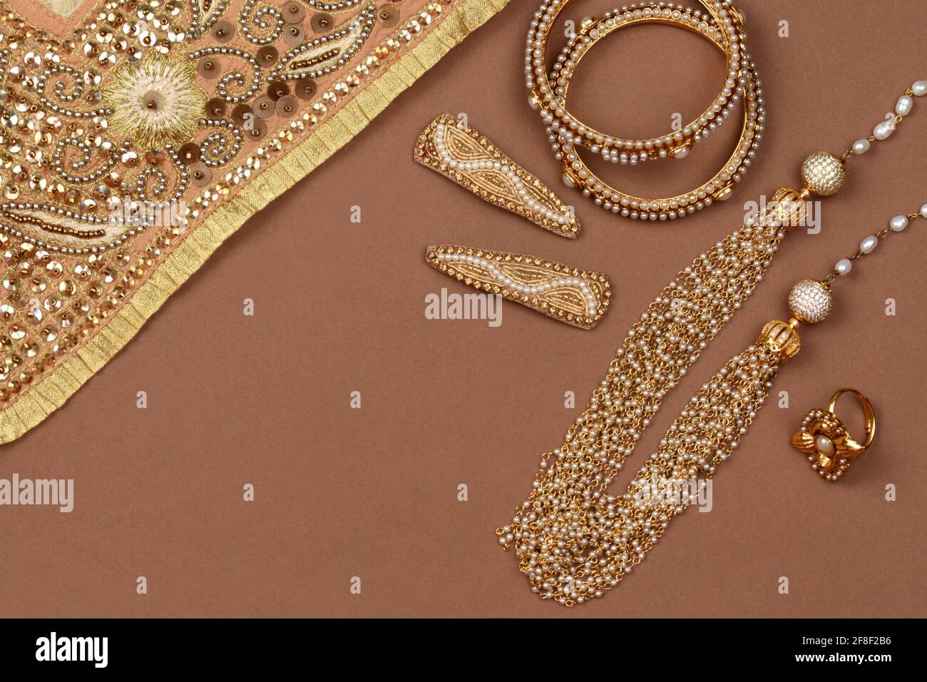 Gioielli Perla su sfondo marrone, sciarpa dorata, bracciale Perla, clip per  capelli perlati, anello per dita perla gioielli tradizionali indiani Foto  stock - Alamy