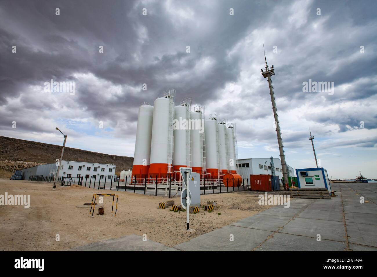 Mangystau, Kazakistan: Baia di Bautino. Terminal di carico e magazzino sul Mar Caspio. Serbatoi di stoccaggio su cielo con nuvole di tempesta grigia. Foto Stock