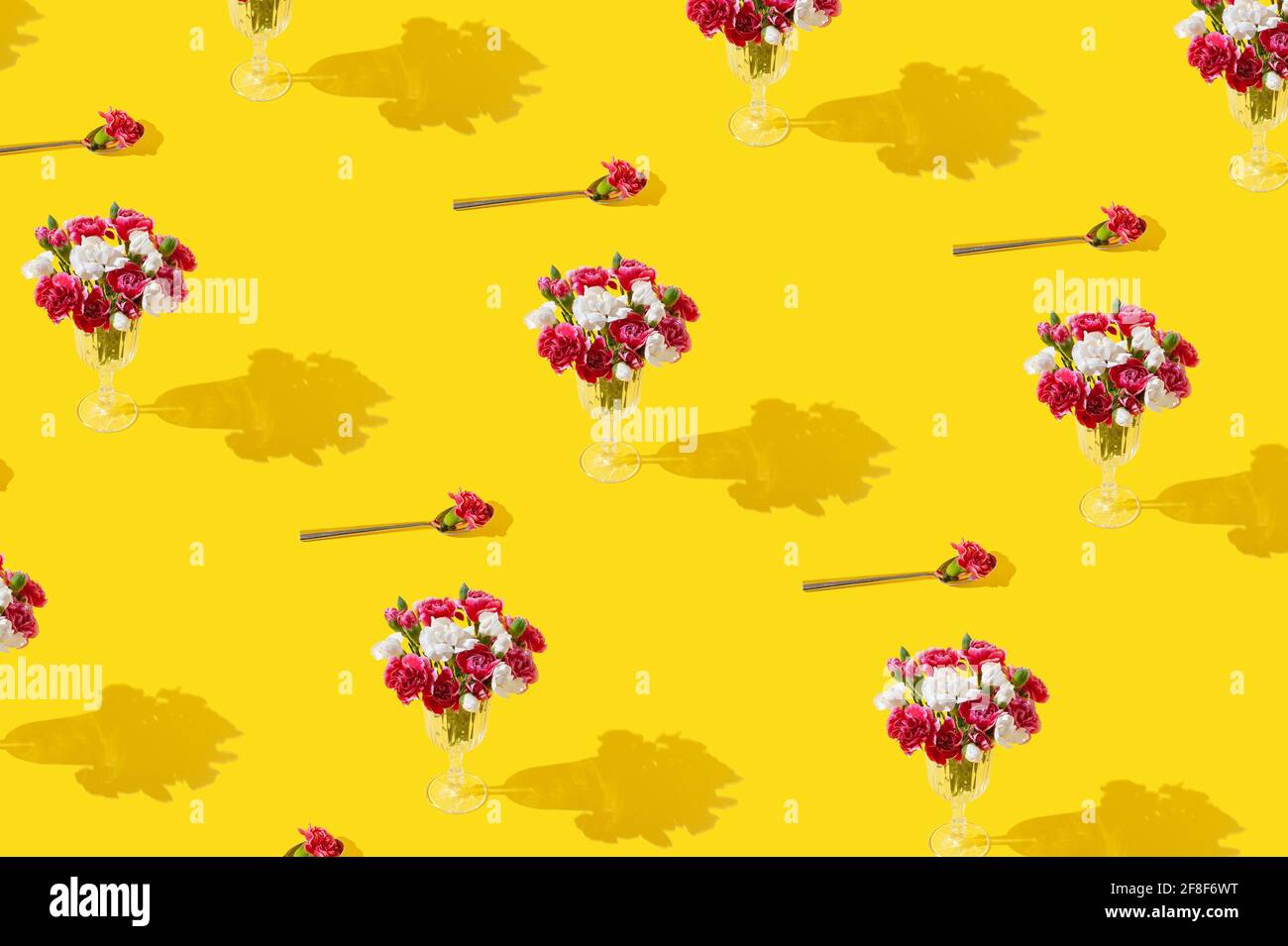 Fiori primaverili in bicchiere di vino su sfondo giallo brillante. Concetto di cibo creativo di stagione minimo. Modello. Foto Stock