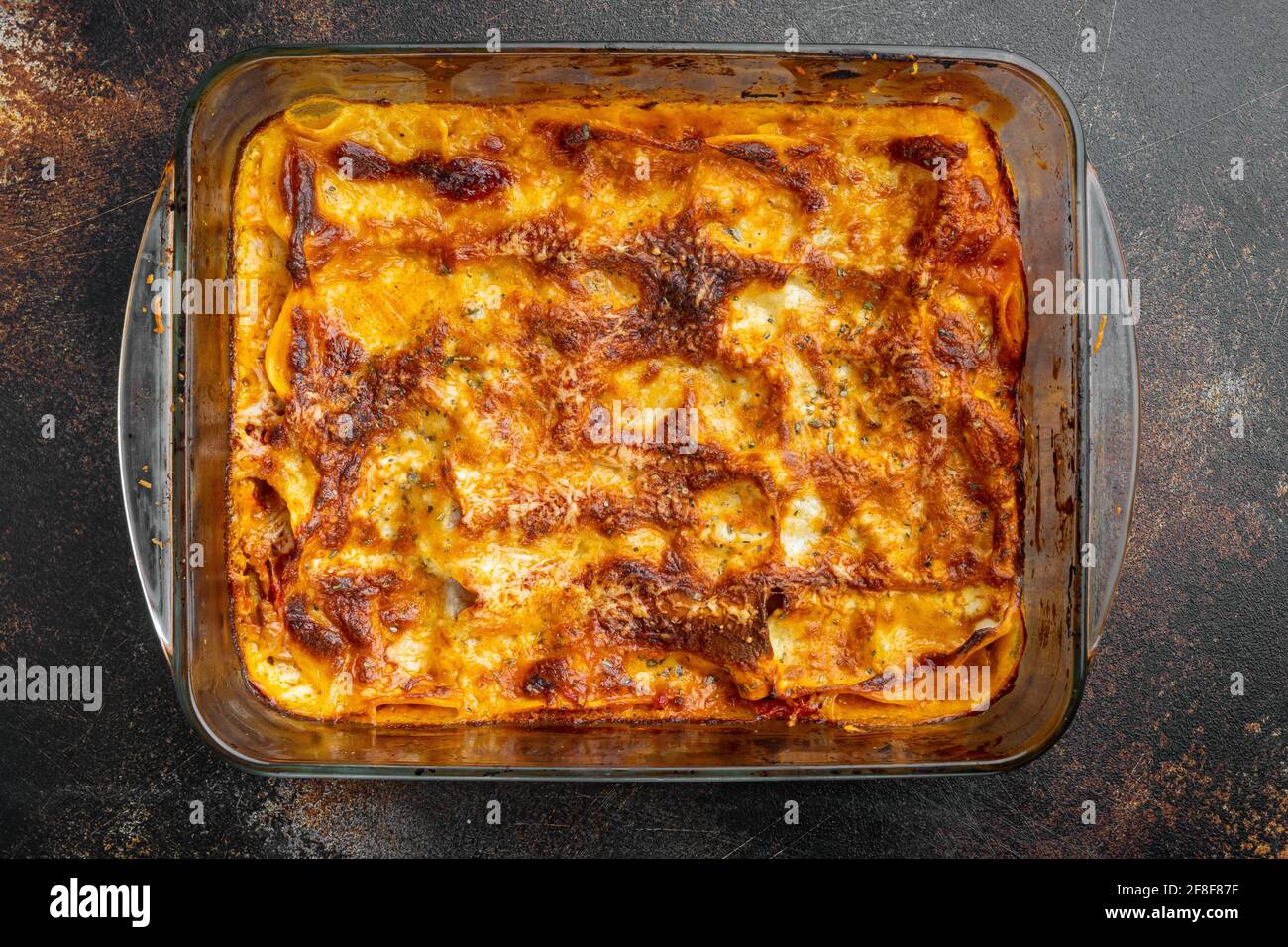 Lasagne tradizionali a base di salsa bolognese di manzo tritato con foglie di basilico, in teglia, su fondo rustico scuro antico, vista dall'alto, piatto Foto Stock