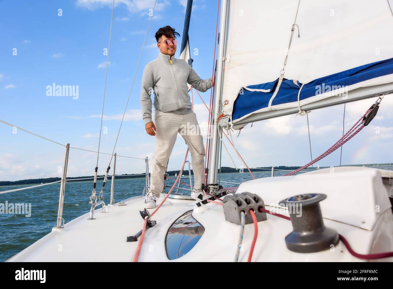 giovane uomo in piedi su una barca a vela. Vacanze estive, crociera, ricreazione, sport, regata, attività di svago, servizio, turismo Foto Stock