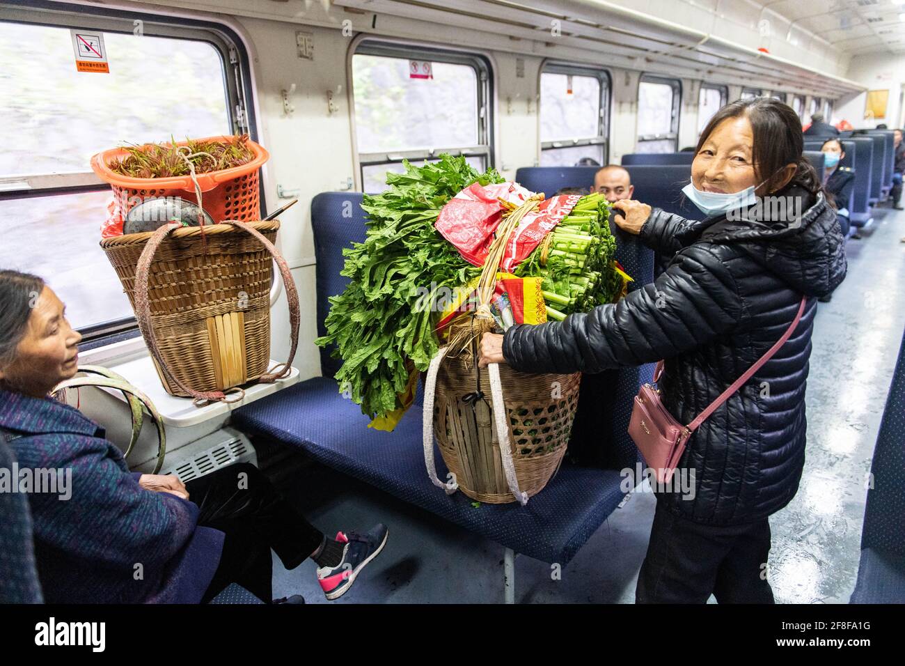 (210414) -- CHANGSHA, 14 aprile 2021 (Xinhua) -- UN passeggero tiene verdure fresche sul treno 7266 nella provincia di Hunan della Cina centrale, 11 aprile 2021. I treni 7265/7266/7267 iniziarono a funzionare nel 1995, estendendosi per più di 300 chilometri dalla stazione di Huaihua alla stazione di Lixian. I treni passano 37 fermate lungo la strada in 9 ore e 16 minuti. I prezzi dei biglietti variano da 1 yuan a 23.5 yuan (circa 0.15-3.59 dollari USA), che non sono stati aumentati in 26 anni. I treni attraversano le montagne di Wuling. Grazie a loro, gli abitanti del villaggio non solo possono trasportare frutta, verdura e altre loca Foto Stock