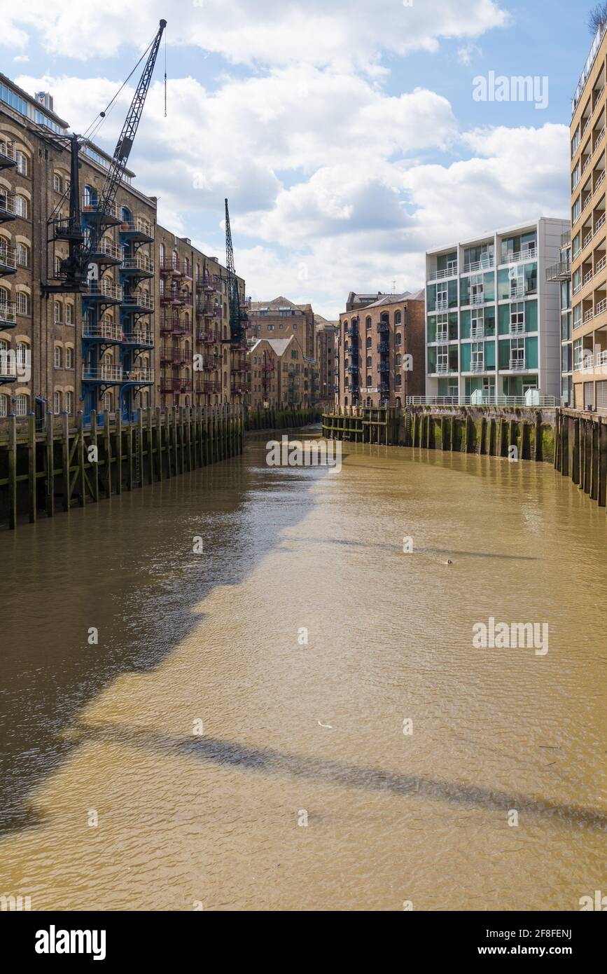 Vista lungo il fiume Neckinger, una riva del Tamigi con vecchi magazzini ora convertiti in blocchi di appartamenti. Bermondsey, Londra, Inghilterra, Regno Unito Foto Stock