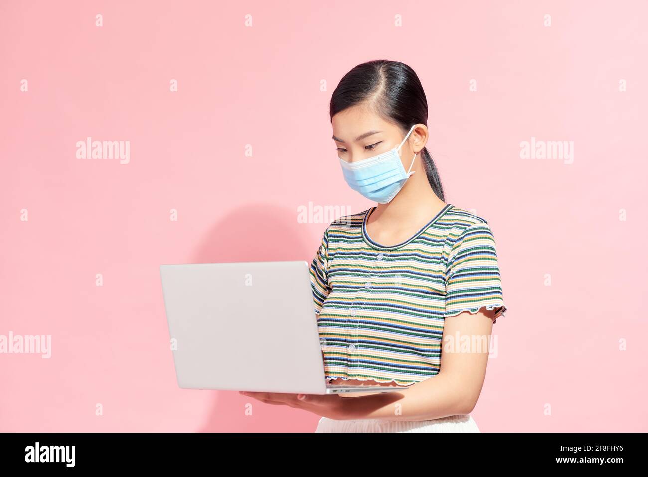 I dipendenti, la donna in ufficio in maschere mediche protettive sono in possesso di computer portatili, malattie contagiose, coronavirus. Foto Stock I dipendenti, la donna in ufficio in maschere mediche protettive sono in possesso di computer portatili, malattie contagiose, coronavirus. Foto Stock