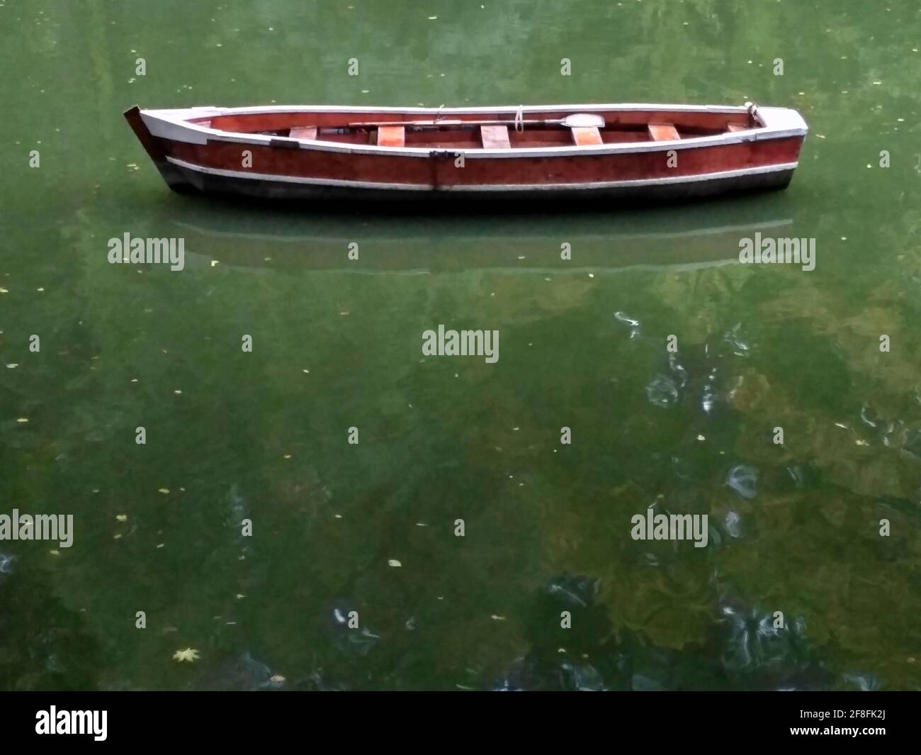 Barca di legno senza persone con il lago verde riflessione acqua, barca a file vista laterale. Foto Stock