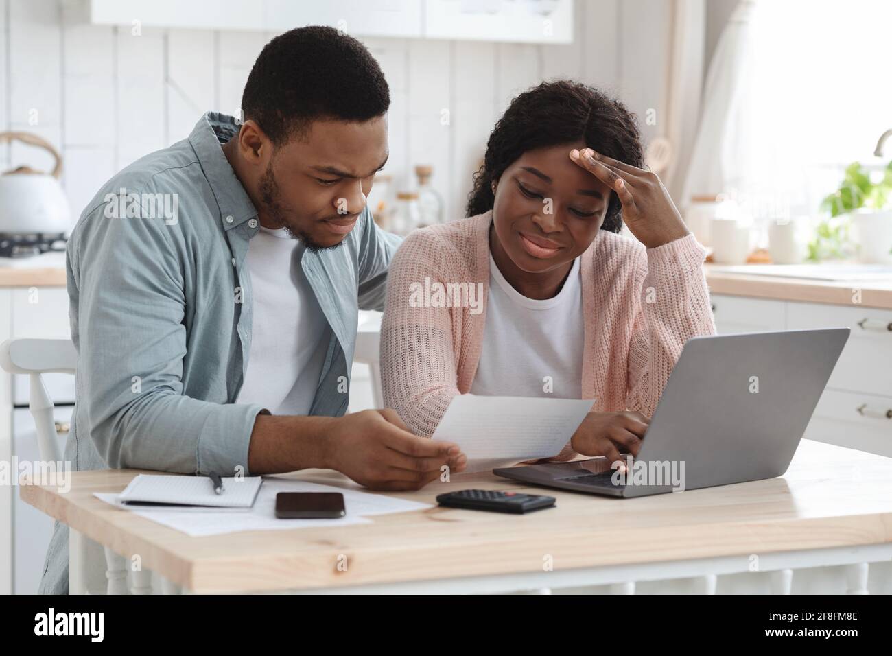 Worry Black coniugi calcolare il bilancio della famiglia in cucina, leggendo i documenti finanziari Foto Stock