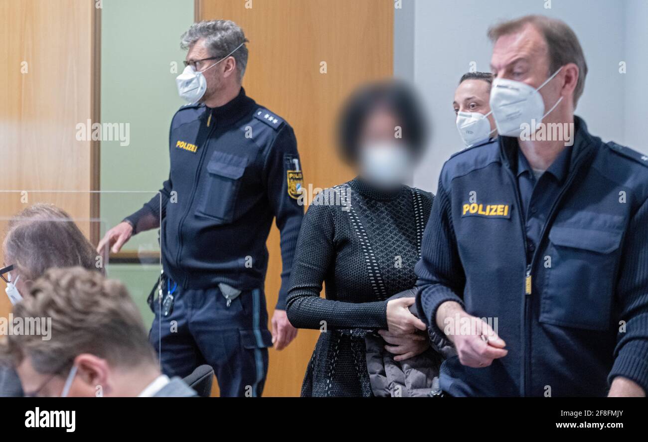 Augusta, Germania. 14 Apr 2021. Due agenti di polizia conducono una donna accusata nella sala della giuria. Gli imputati sono accusati di aver accusato le compagnie di assicurazione di assistenza infermieristica di milioni di persone tramite fatturazione per i servizi di assistenza che non sono stati forniti. Credit: Stefan Puchner/dpa - ATTENZIONE: Gli imputati sono stati pixelated per ordine della difesa/dpa/Alamy Live News Foto Stock