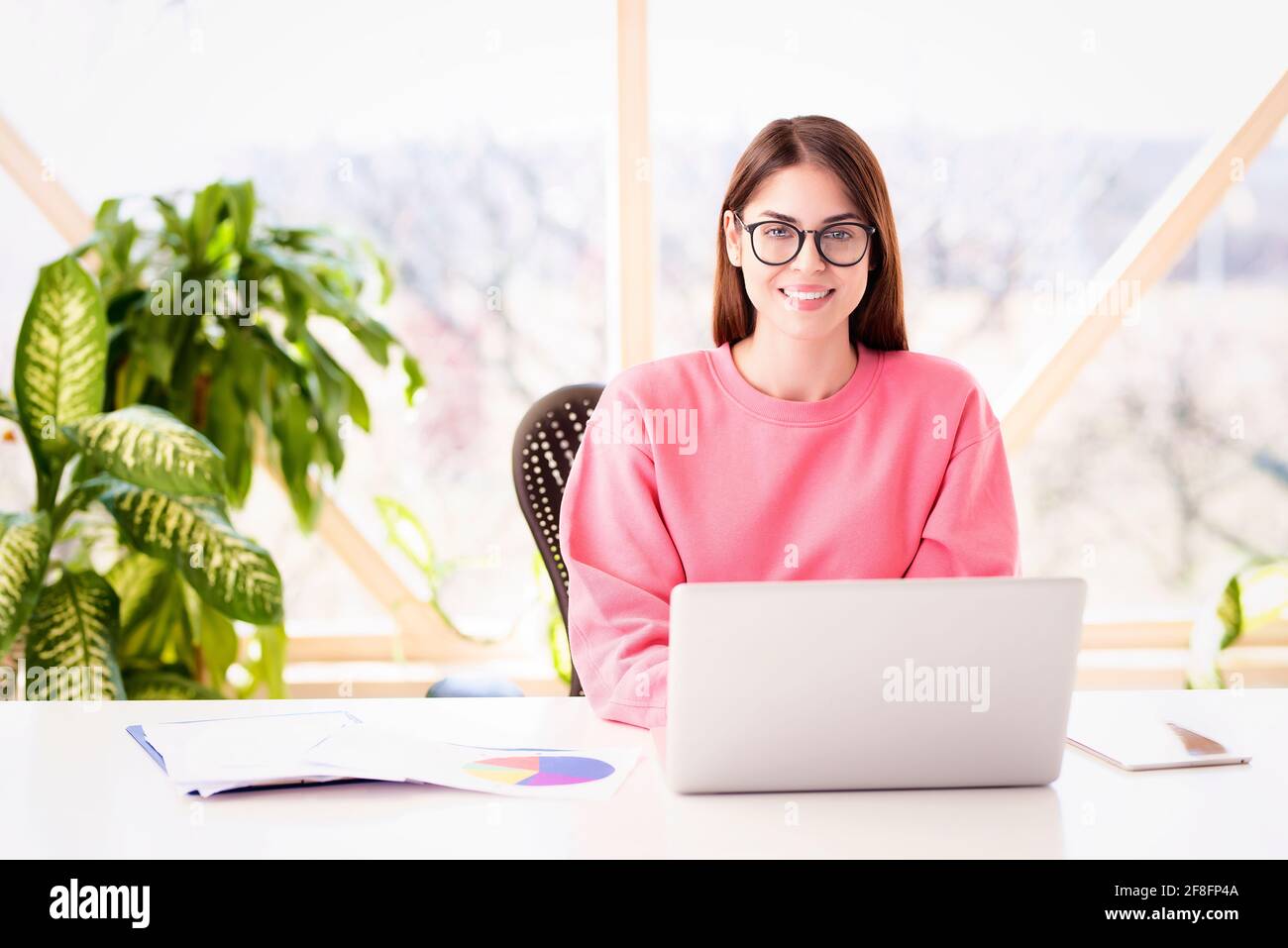 Foto di una donna d'affari sorridente seduto alla scrivania e che lavora su un computer portatile. Ufficio domestico. Foto Stock