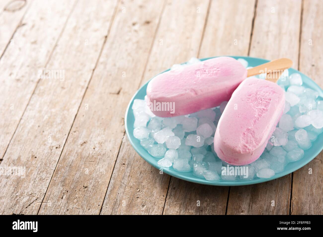 Popsicle di fragole e ghiaccio tritato su tavola di legno Foto Stock