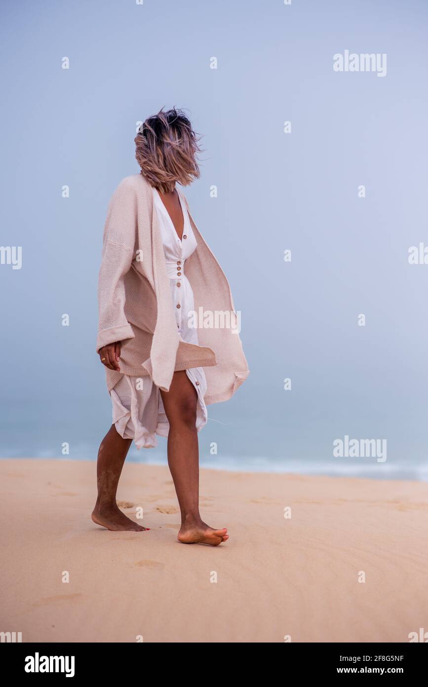Donna che cammina lungo la duna di sabbia con l'oceano in background Foto Stock