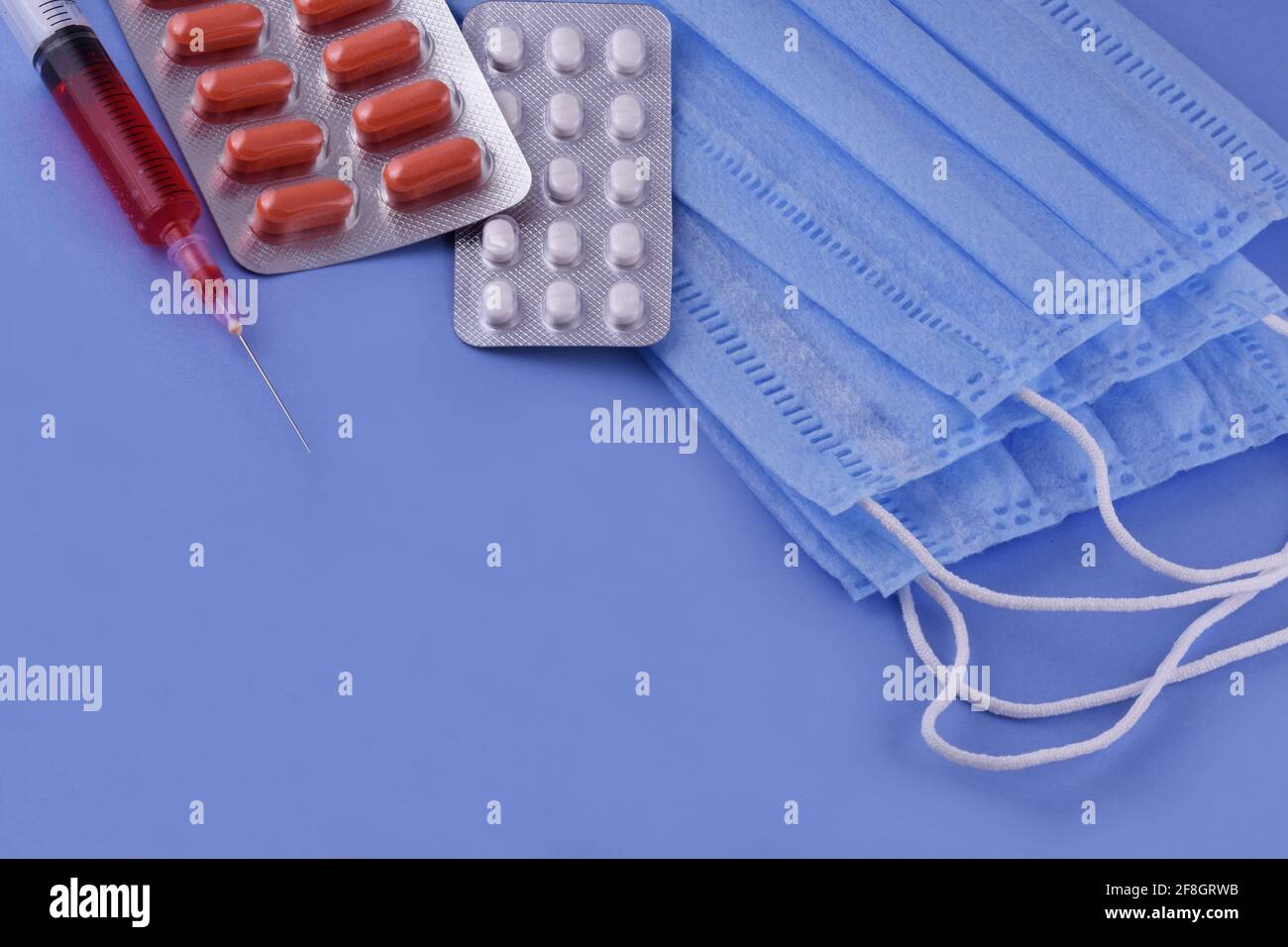 Maschera medica protettiva, pillole, siringa su sfondo blu, protezione da virus corona, coronavirus, covid19 pandemia globale Foto Stock